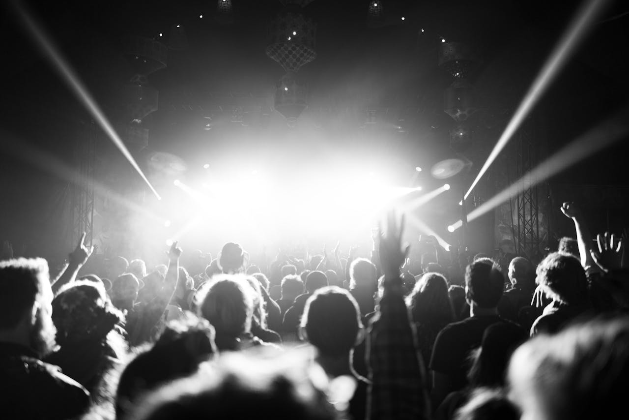 Dynamic black and white image capturing a lively crowd at a Glastonbury music festival.