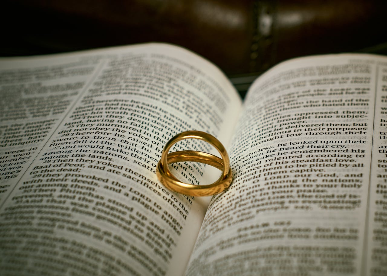 Golden wedding rings resting on an open Bible, symbolizing love and faith.